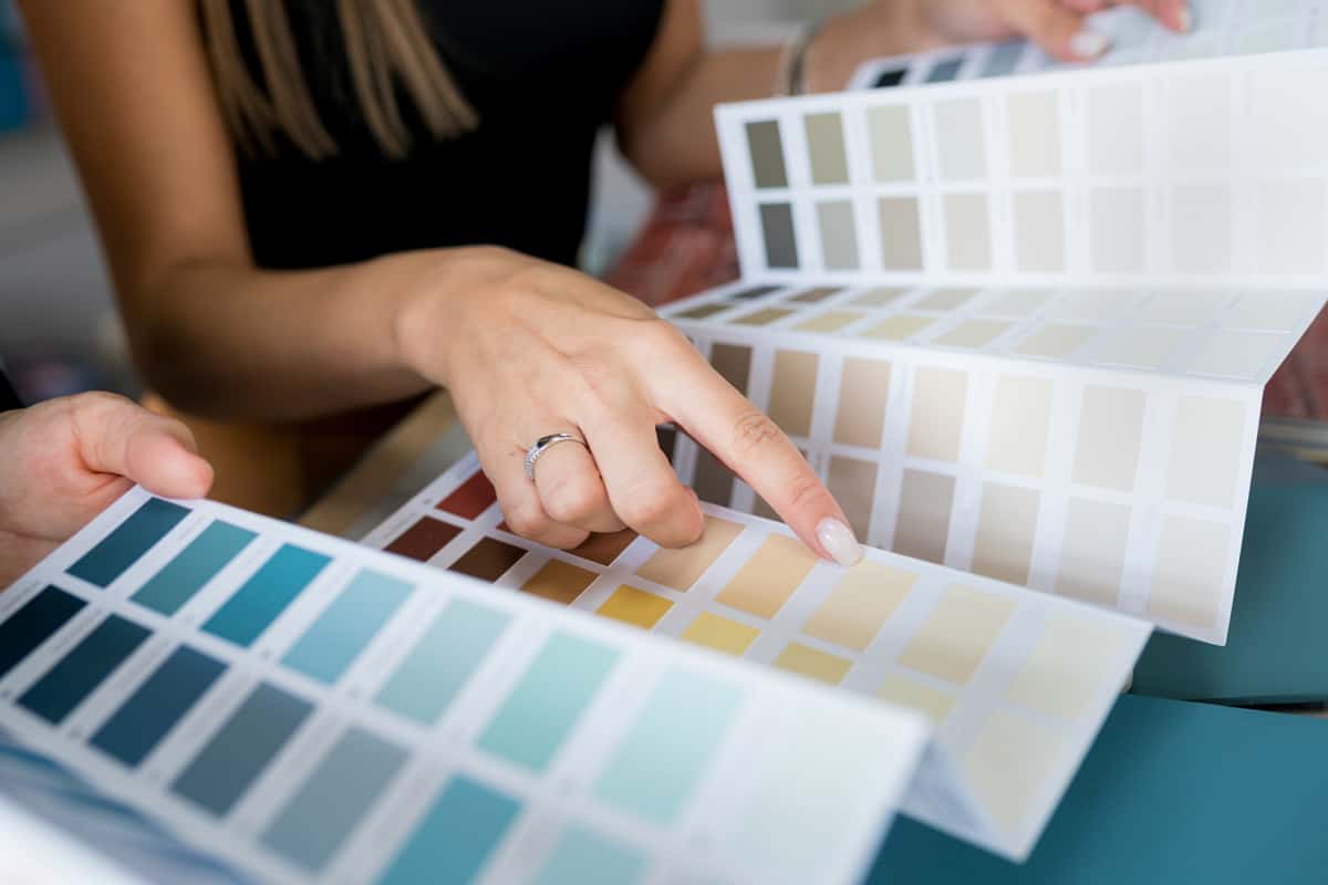 Close-up of two women choosing samples of wall paint. Interior designer consulting a client looking at a color swatch.