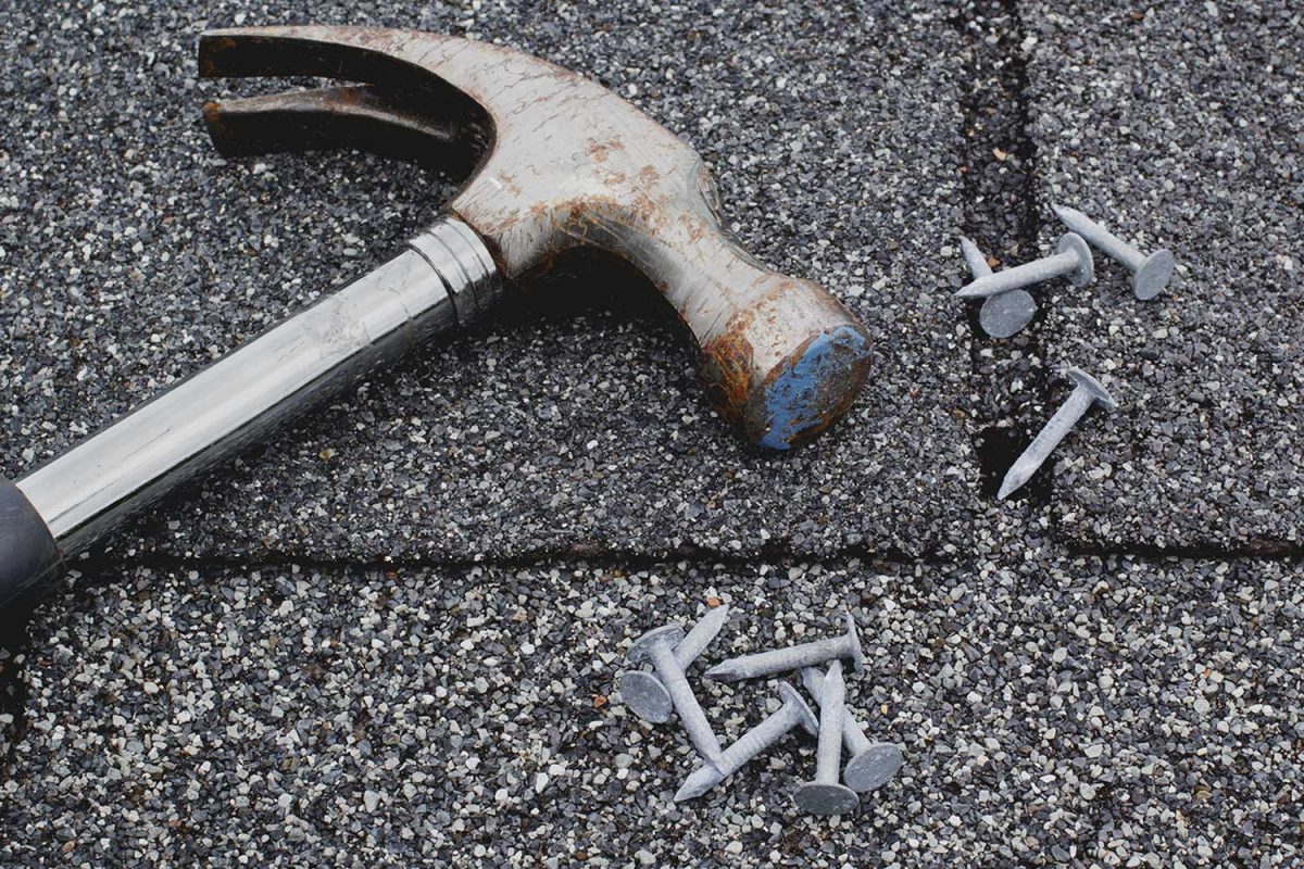 Hammer and roofing nails on rooftop shingles