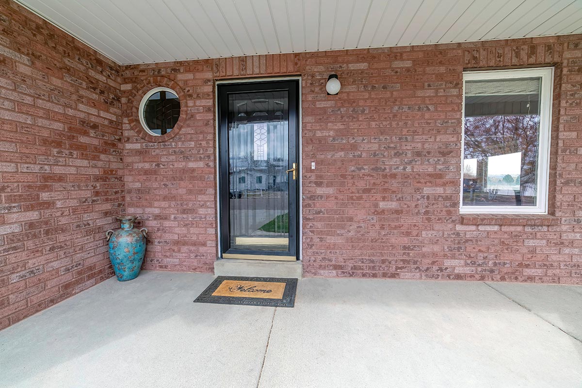 House entrance with glass storm door and front door against red brick wall