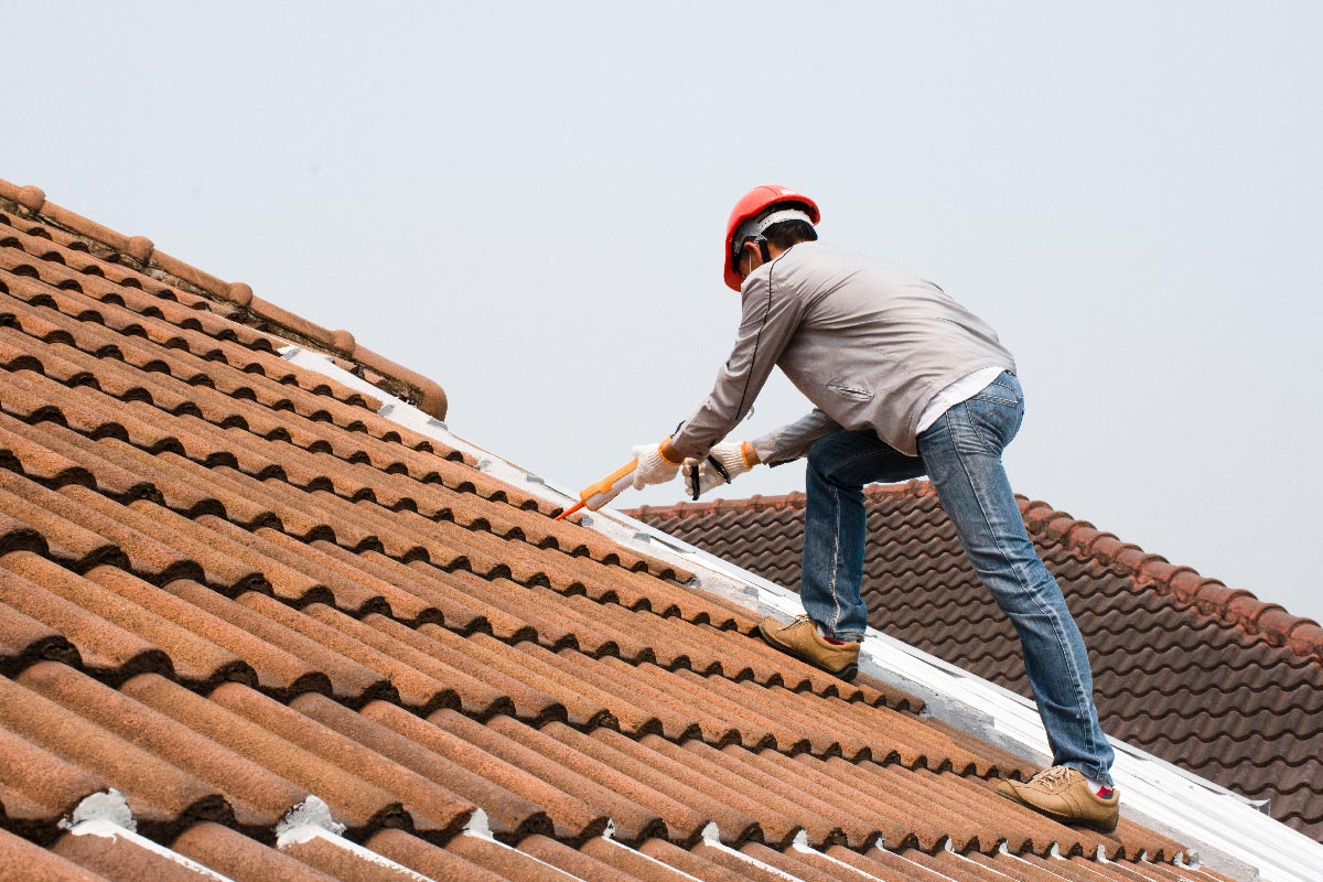 A man using glue gun with silicone adhesive seal the leakage on the roof