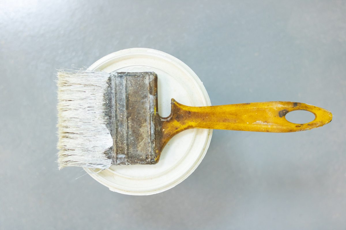 Paint brush and can of paint on a gray floor, top view

