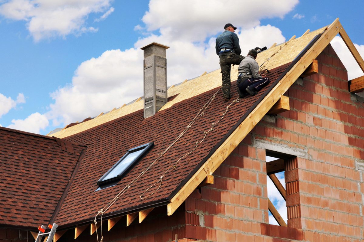 Roofers lay and install asphalt shingles. Roof repair with two roofers. Roofing construction with roof tiles