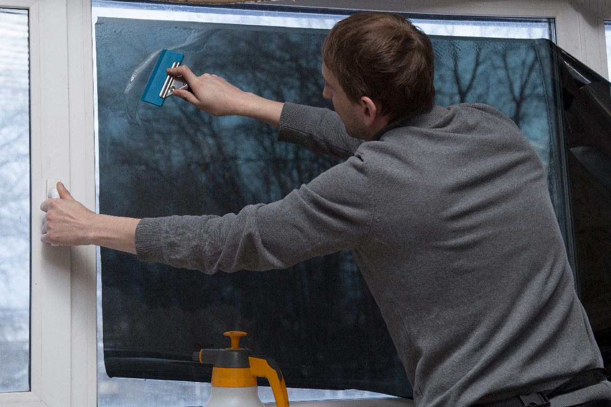 Worker removing bubbles on window film