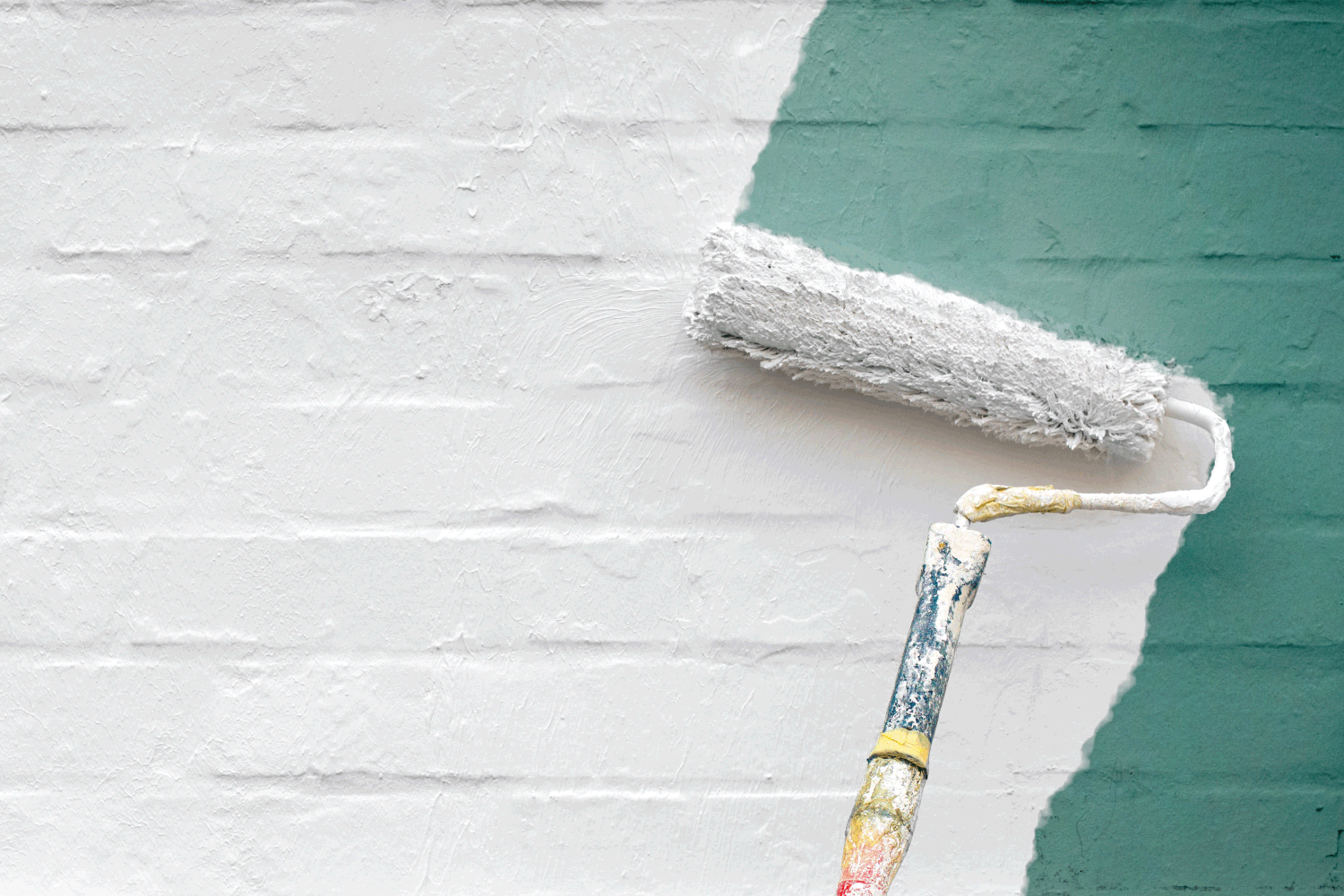 paint roller applying green coat of paint over white brick wall