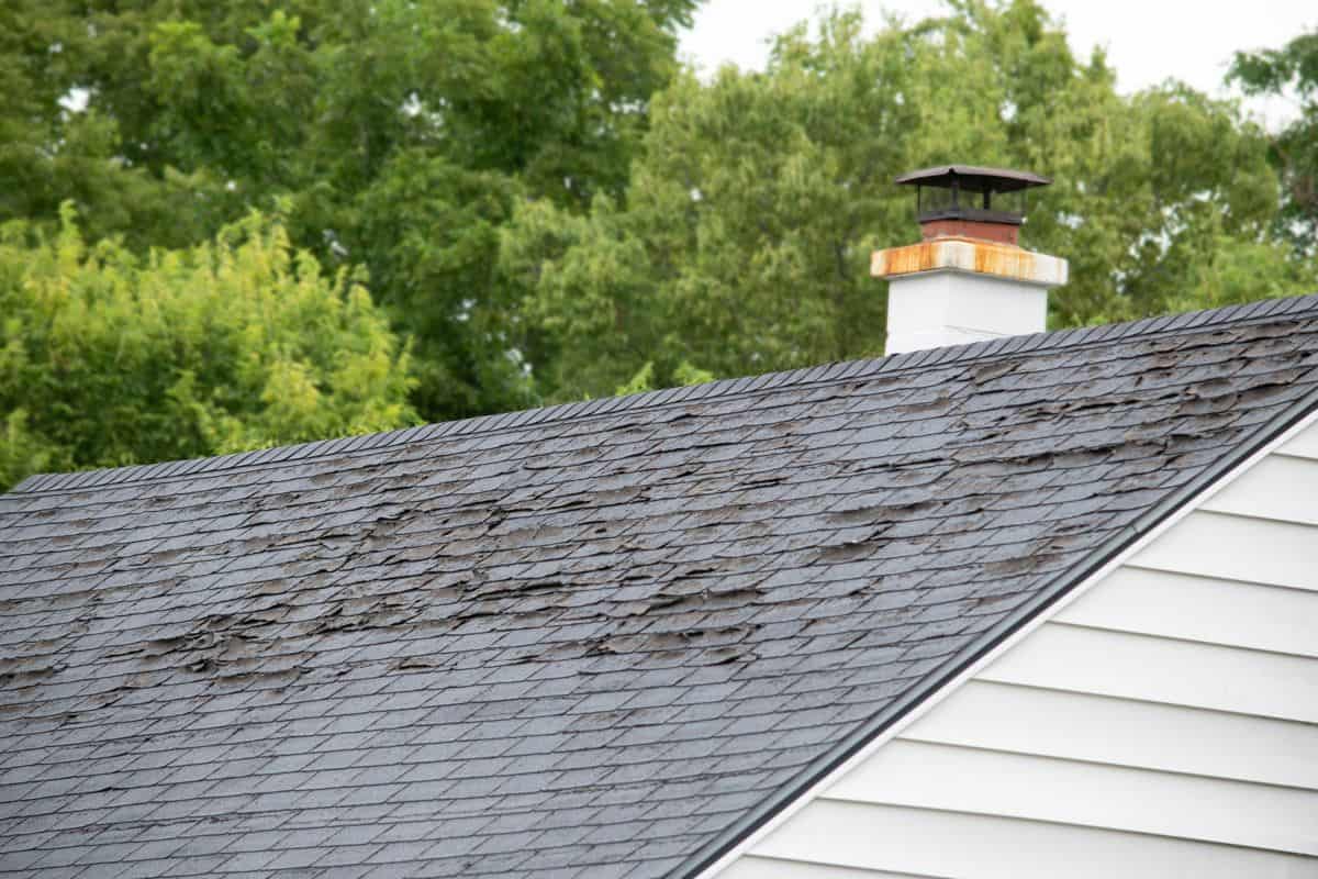 Damage to asphalt and asbestos shingles, gutter systems, chimney and roof flashing on residential home.