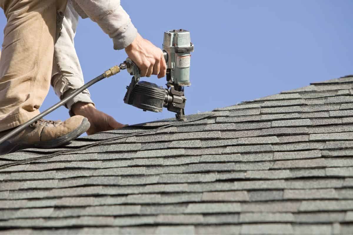 Roofer Nailing Cap Shingle to a New House Roof 