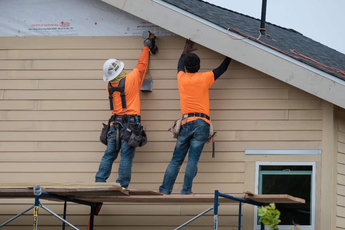 Why Should You Not Directly Apply Vinyl Siding To Studs - Construction workers installing vinyl siding facade on scaffolding system.