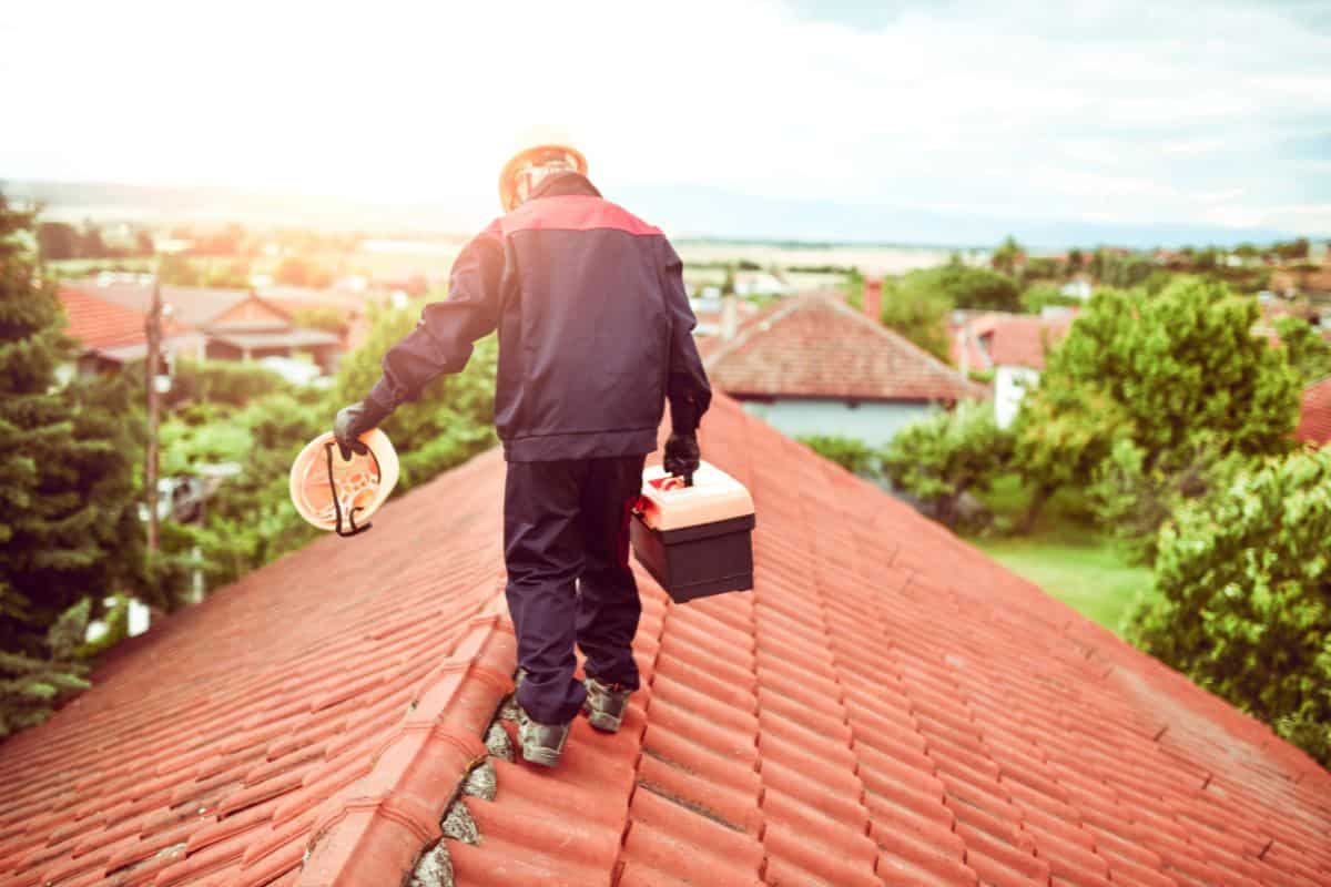 Worker Carrying Toolbox On House Rooftop