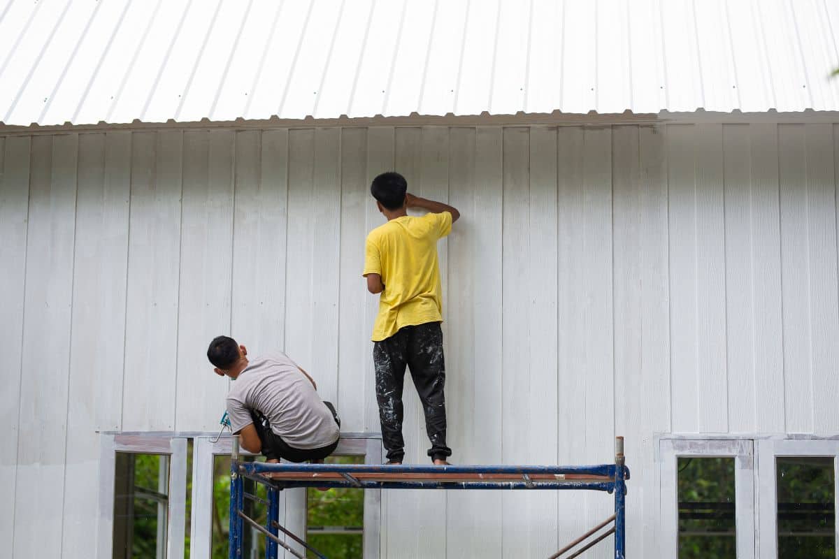 Workers are painting or repairing houses or walls on scaffolding by dressing without protective equipment to ensure work safety. Work safety guidelines
