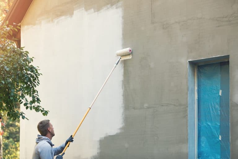 House painter painting building exterior with roller stock photo. - How To Paint Outside Of House Without Scaffolding