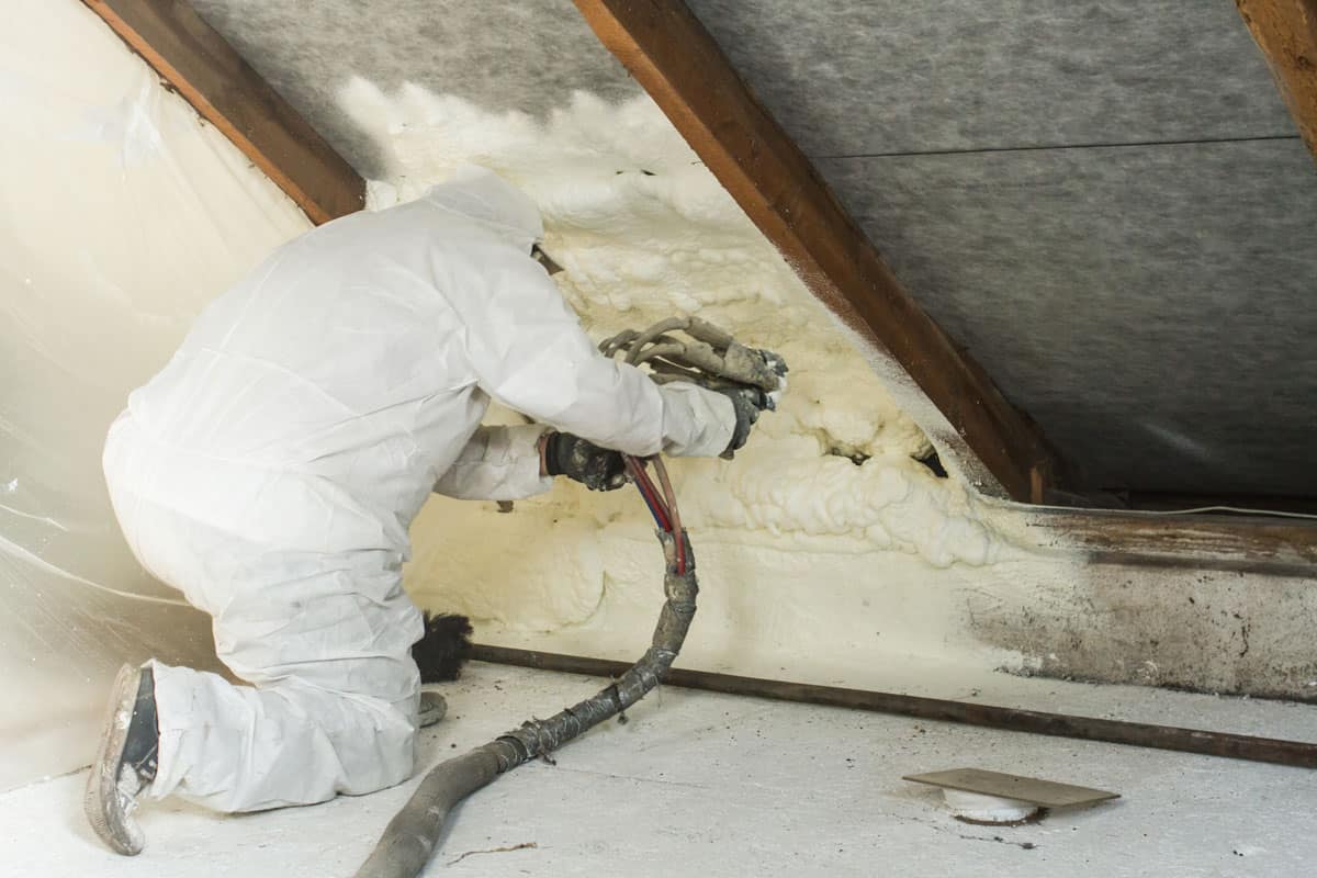man wearing safety gears and suits installing a roof insulator inside the roof