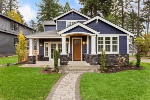 Beautiful exterior of newly built luxury home. Yard with green grass and walkway lead to ornately designed covered porch and front entrance.- 7 Exterior Paint Colors That Look Like Wood