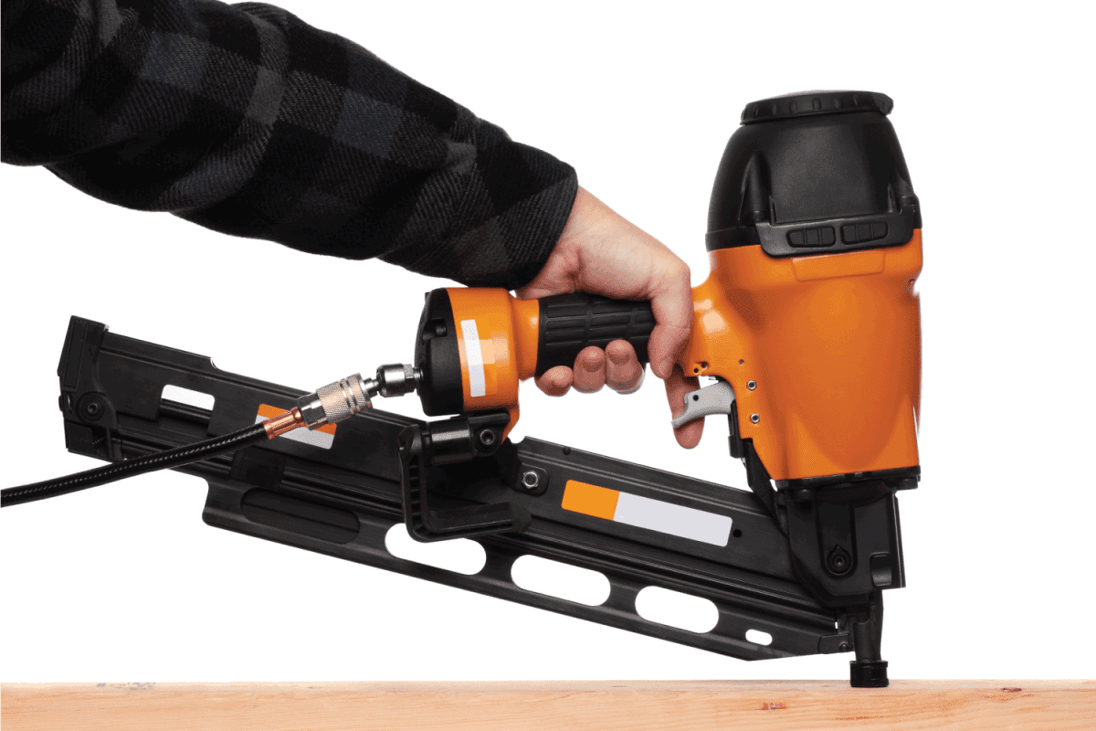 Man using a framing nailer on a 2x4 stud against a white background.