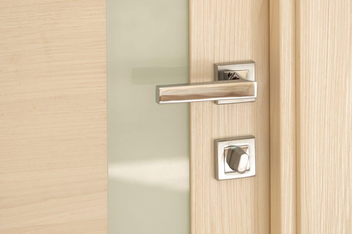 Modern light stylish door fragment with a glass strip with a nickel-plated handle and latch
