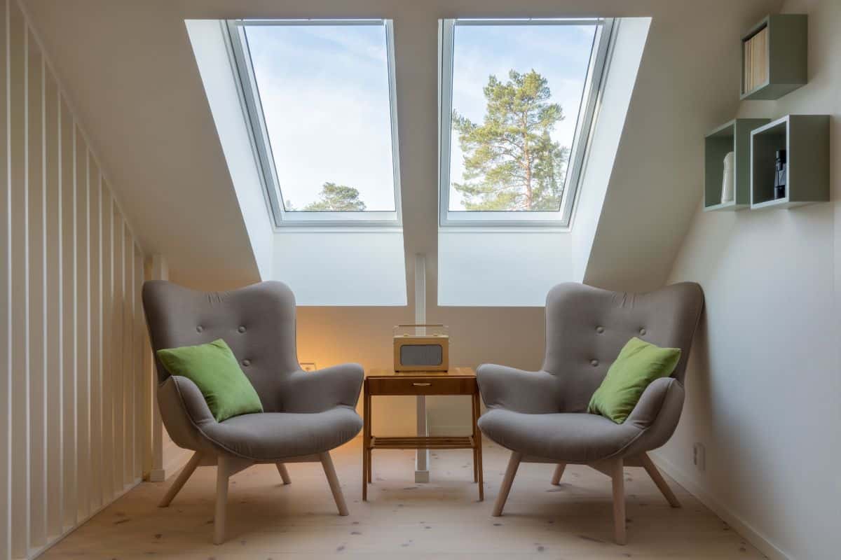 Modern retro design in a attic / loft. Small vintage table with a radio on and two reading chairs under two skylights. Roof / ceiling window.