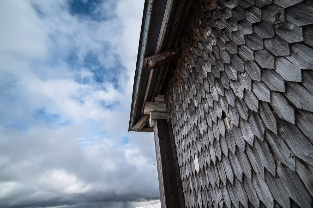 Can Old Cedar Siding Be Restored?Wooden house in the snowy mountains. Wall and roof covering with natural shingle.