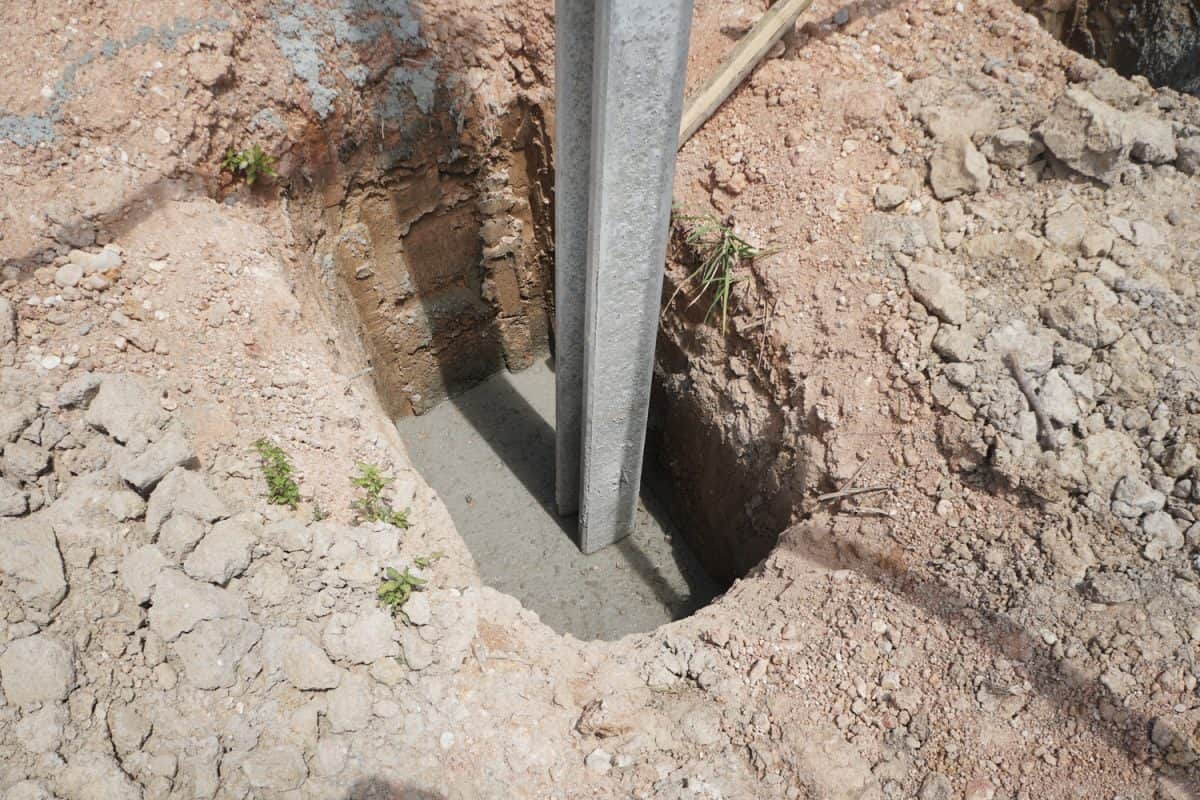 Concrete footings and i beam concrete pile for fences that are installed in hole on construction site.
