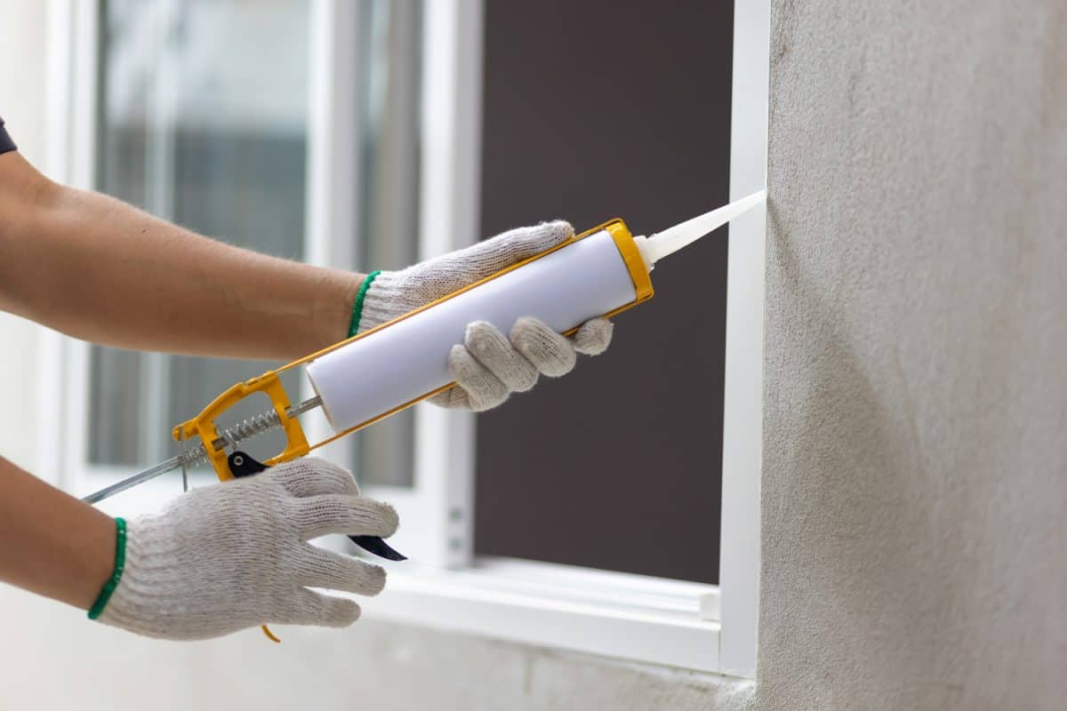 Construction worker using silicone sealant caulk the outside window frame.
