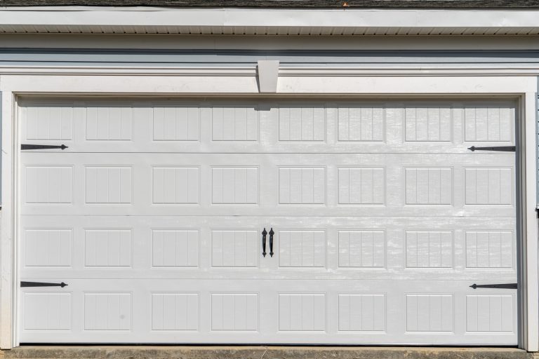 Double car classic insulated steel raised panel garage door framed with a white trim to add accent, on a new American home - How To Finish Garage Door Trim